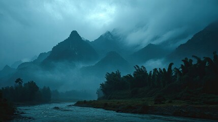 A moody, atmospheric landscape photograph of a river winding through a misty valley, with dark, imposing mountains shrouded in fog in the background and lush vegetation along the riverbanks