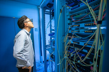 Professional Man Examining Server Rack in Modern Data Center Environment