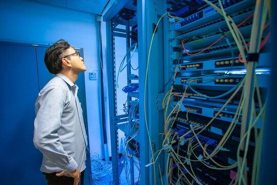 Professional Man Examining Server Rack in Modern Data Center Environment