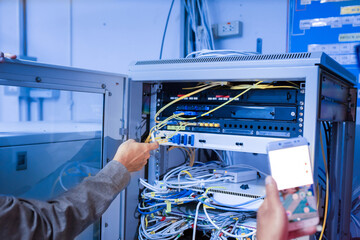 Technician Working with Network Equipment and Cables in Server Room