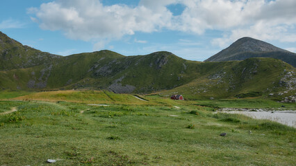 Picturesque Lofoten beach with red cabin, blue sky and Nordic landscape