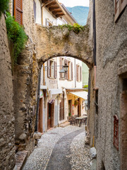 Charming cobblestone alley in Malcesine, Italy, lined with colorful houses, flower pots, and balconies draped in greenery. A peaceful, picturesque glimpse of traditional Italian village life.