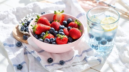 Summertime Still Life: Refreshing Fruits in a Pink Bowl and Iced Lemon Water on a Sunny Table.