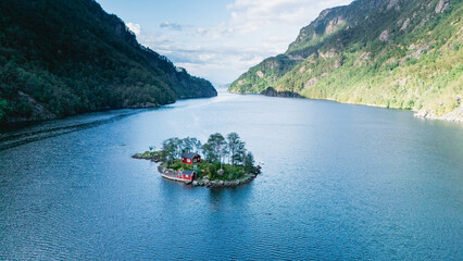 Lovrafjorden showcases a stunning aerial view of a charming red cabin nestled on a tiny island,...