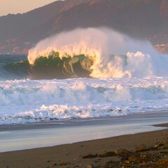 Majestic ocean wave crashing on a beach at sunset