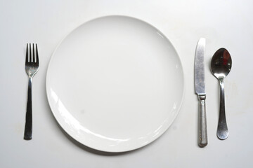White plate, dish with fork and knife, spoon on the table