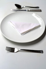 Table arranged with fork and knife, spoon, white plate