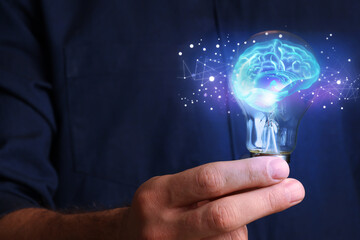 Man holding light bulb with brain illustration inside, closeup. Idea concept