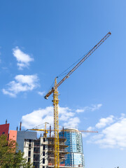 Modern construction crane on skyscraper and blue sky background.