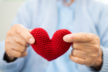 Asian elder senior woman patient holding red heart in hospital.