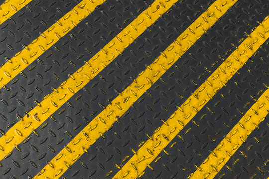 Industrial black and yellow diagonal stripes painted on a metal surface