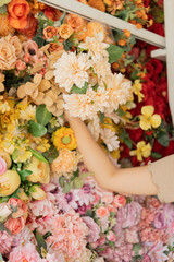 Asian female florist in apron smiling while designing a beautiful floral arrangement with her colleague in a flower shop. Concept of teamwork, creativity, floral business, and joyful workplace.