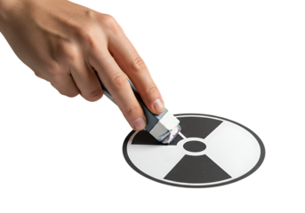 Hand erasing radiation symbol on white surface, representing the removal of nuclear threat and promotion of safety and peace, conveying a sense of hope and security.