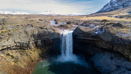 Salto del Agrio waterfall plunges into a turquoise pool surrounded by rocky terrain. Neuquen, Argentina
