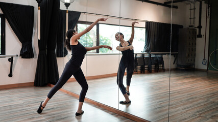 A graceful ballet dancer rehearsing in a studio, practicing her routine