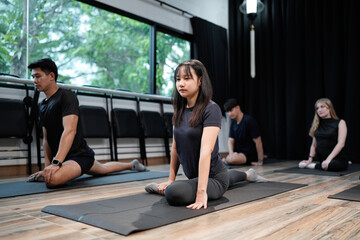 Diverse sporty men and women doing stretching exercises during group yoga lesson