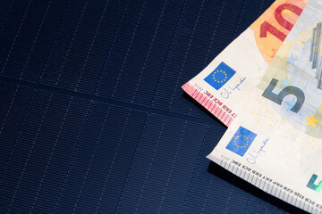 Euro banknotes on solar panel surface close-up, concept of renewable energy investment and financial savings.