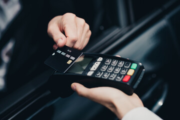 Obraz premium Person conducting a contactless payment with a credit card at a wireless terminal in a modern setting