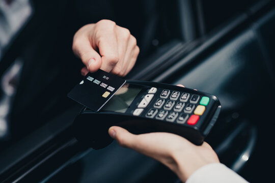 Person conducting a contactless payment with a credit card at a wireless terminal in a modern setting
