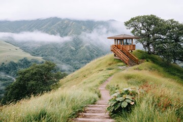 Naklejka premium Scenic Hilltop Gazebo Surrounded by Lush Green Hills and Misty Mountains Captured on a Cloudy Day in a Tranquil Natural Environment