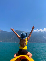 Girl is sailing on a boat on the lake and enjoying the view of the mountains. Canoeing and kayaking on the lake. Active sports recreation on the lake.