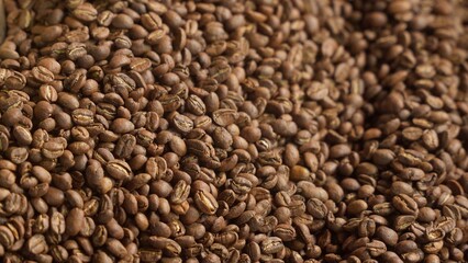 Close up roasted coffee beans mixing in mixer roaster blend automatic metal drum machine stirring roasting cocoa caffeine at production facility aromatic grains in grinder industrial food preparation
