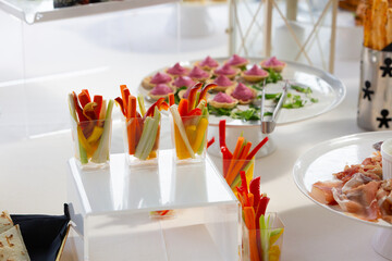 Colorful vegetable sticks served in elegant glasses at a buffet table