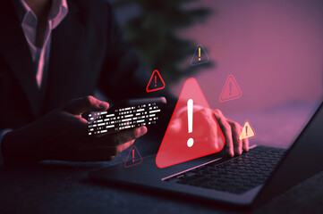 Businessman holding phone with digital alert symbols on screen, illustrating data breach warning, system vulnerability, or malware attack detection in cybersecurity.