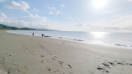 Beautiful beach scene with clear blue sky, sparkling ocean water, and people strolling along the sandy shore. Perfect for travel and vacation themes.