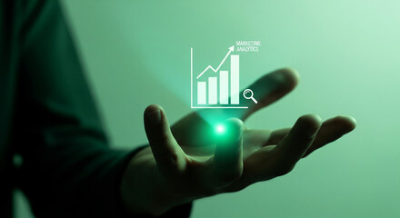 Businessman's hand holding a glowing green hologram of a rising bar chart, representing marketing analytics, data-driven strategy and corporate success
