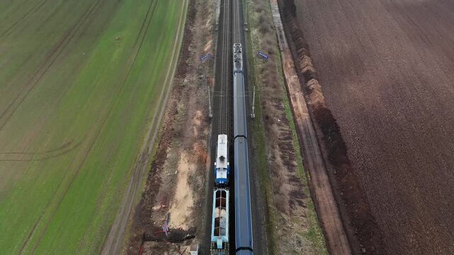 Aerial drone view of work train moving opposite to passenger train on parallel railway tracks, symbolizing transport flow, logistics, infrastructure, and mobility.
