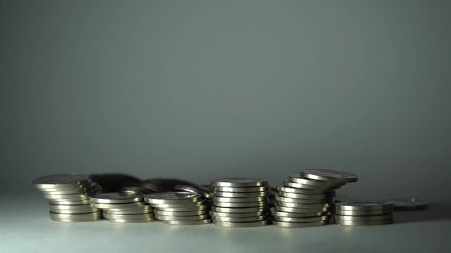 Hand pushes a coin pyramid; tall stack topples and scatters downward, illustrating fragility, financial instability, cascading collapse, risk, and loss of controlled savings.
