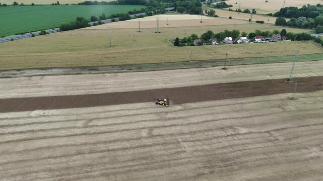 Aerial drone footage of a combine harvester cutting a golden wheat field, showcasing modern agriculture, grain harvest, rural landscape, and seasonal farming productivity.