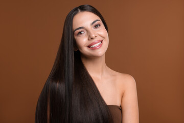 Woman with beautiful smooth hair after lamination procedure on brown background