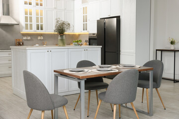 Kitchen interior with dining table, place setting and grey chairs