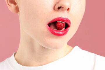 Woman with beautiful lips makeup and raspberry on dusty pink background, closeup