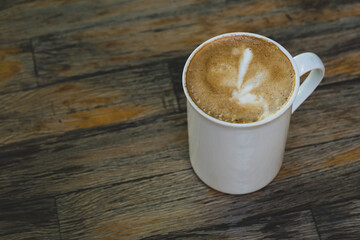 Latte in White Cup on Wooden Table. Cozy Latte Coffee Cup on Wooden Background. Morning Latte in Ceramic Mug on Wood Table.