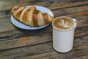 Latte Coffee and Croissant on Wooden Table. Cup of Latte and Croissant Morning Snack. Delicious Latte with Fresh Croissant on Table. Fresh Croissant with Cup of Latte.