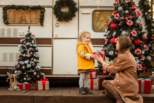 happy family of mother and daughter celebrating Christmas near the trailer with Christmas decorations