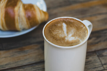 Latte Coffee and Croissant on Wooden Table. Cup of Latte and Croissant Morning Snack. Delicious Latte with Fresh Croissant on Table. Fresh Croissant with Cup of Latte.