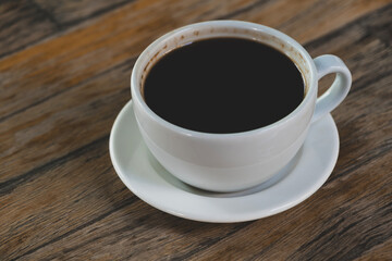 Cup of coffee on wooden table. Hot coffee in a cup on rustic wooden surface. Warm beverage on wooden background.