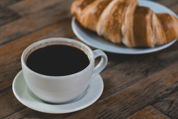 Fresh croissant and hot coffee. Cup of coffee and croissant. Breakfast with coffee and croissant. Cup of coffee with croissant on table.