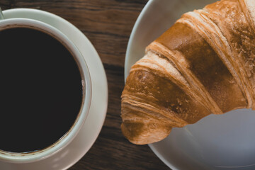 Fresh croissant and hot coffee. Cup of coffee and croissant. Breakfast with coffee and croissant. Cup of coffee with croissant on table.