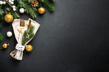 Modern golden cutlery and christmas decorations at black.