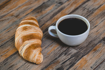 Fresh croissant and hot coffee. Cup of coffee and croissant. Breakfast with coffee and croissant. Cup of coffee with croissant on table.