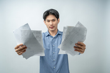 A stressed and anxious young man expresses shock and despair while reviewing numerous overdue bills...
