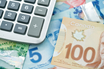 Calculator with Canadian dollar banknotes in background.
