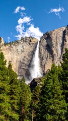 Majestic waterfall cascading down a granite cliff face, surrounded by lush green forest