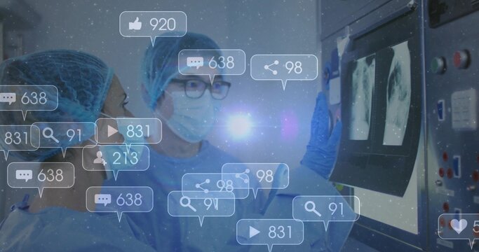 Reviewing scans surgeons wearing blue gowns standing in radiology room, with social media icons - Powered by Adobe