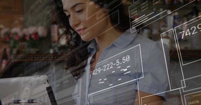 Barista holding tablet device and examining data overlays in wooden cafe, with flowers - Powered by Adobe